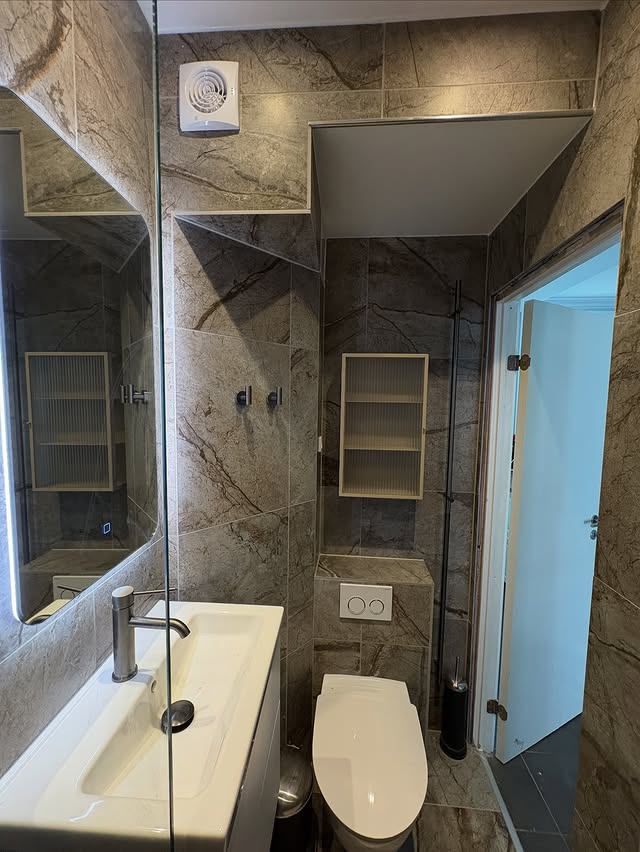 Badeværelse efter renovering – nye fliser, vask og toilet